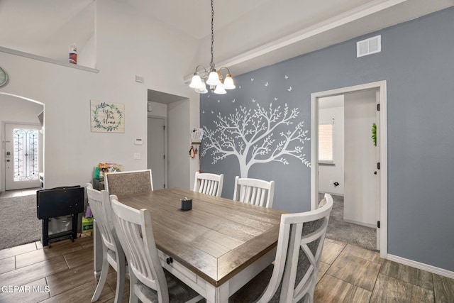 dining area featuring visible vents, arched walkways, an inviting chandelier, and wood tiled floor