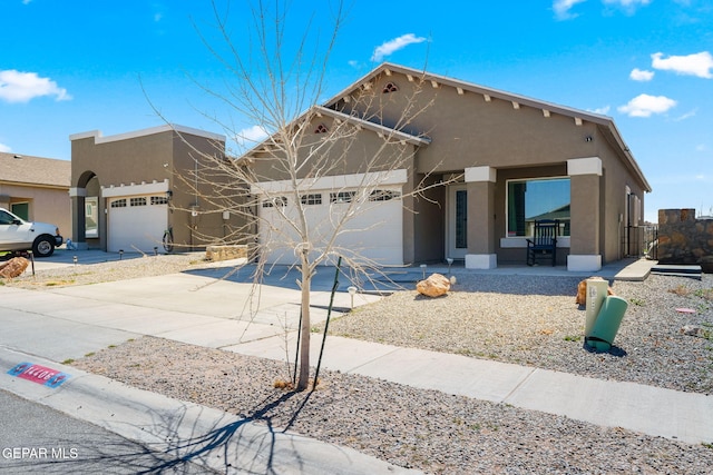 pueblo revival-style home featuring an attached garage, driveway, and stucco siding