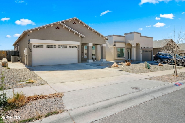 pueblo-style home featuring an attached garage, central air condition unit, stucco siding, driveway, and a gate