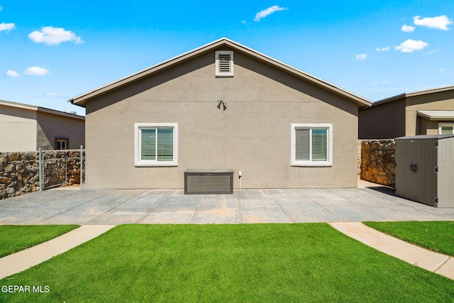 back of property featuring a patio area, stucco siding, a lawn, and fence