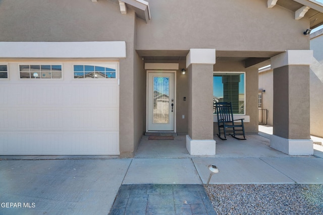 view of exterior entry featuring a garage and stucco siding