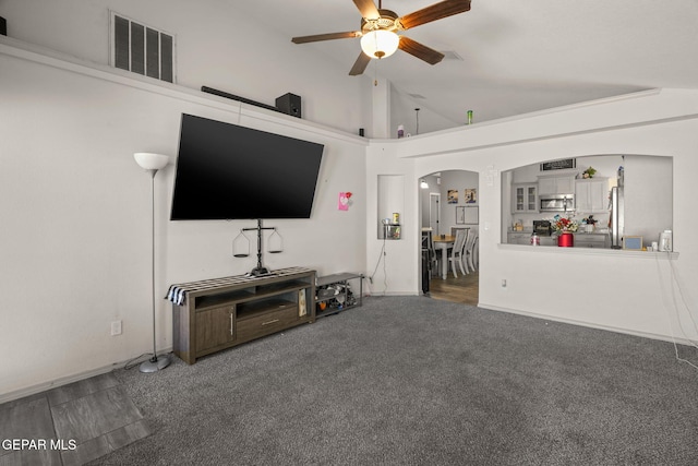 carpeted living area with arched walkways, visible vents, a ceiling fan, and lofted ceiling