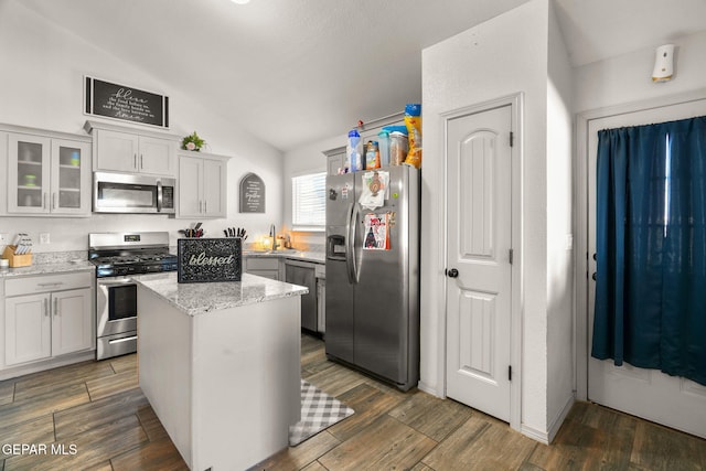 kitchen with a sink, appliances with stainless steel finishes, dark wood finished floors, and vaulted ceiling