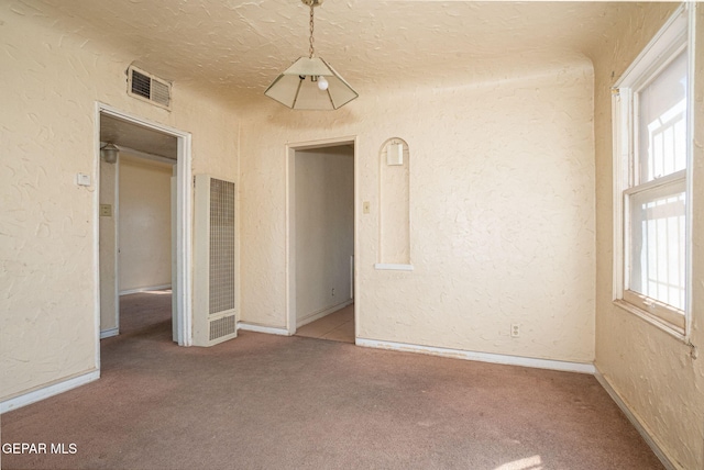 unfurnished room featuring plenty of natural light, a heating unit, and a textured wall