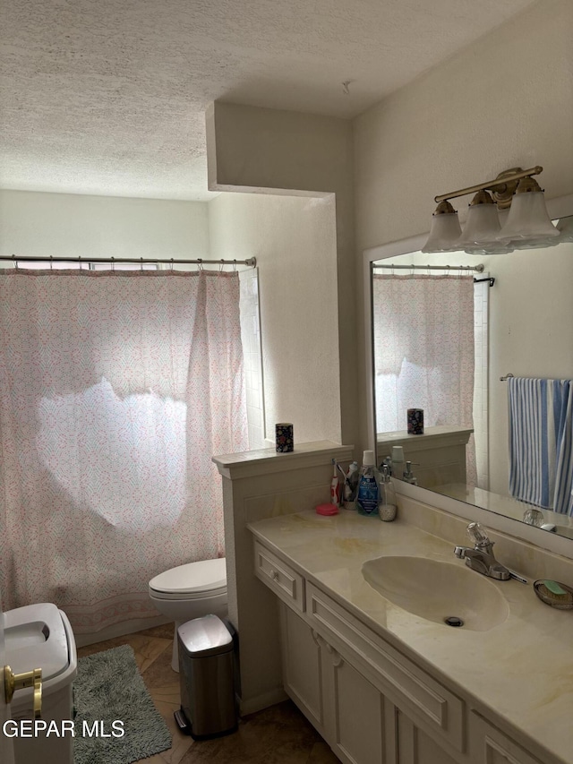 bathroom with a textured ceiling, toilet, and vanity