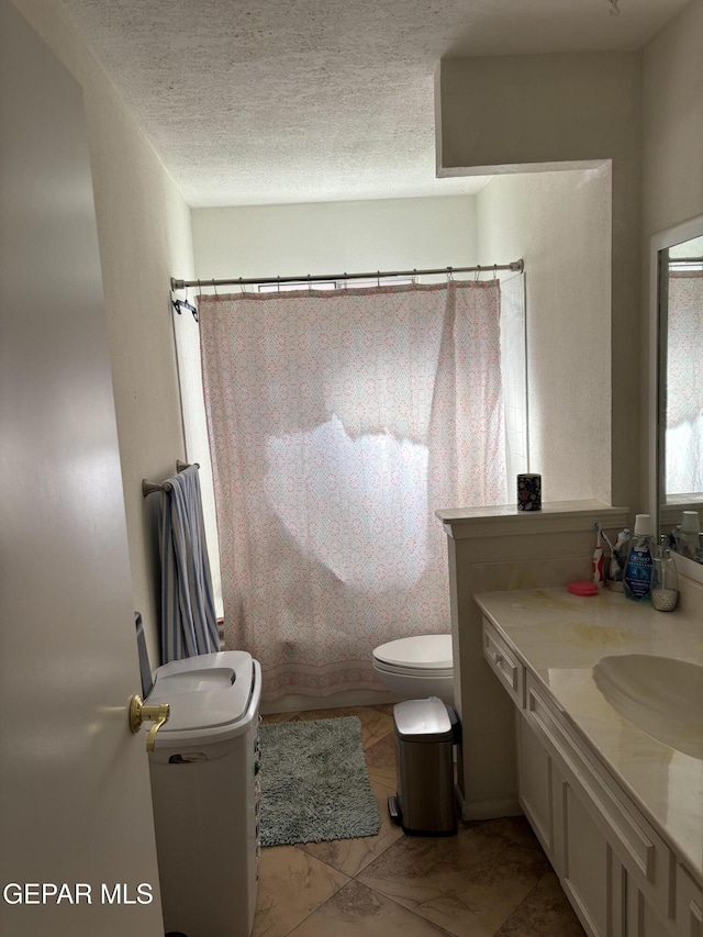 full bath with toilet, vanity, and a textured ceiling