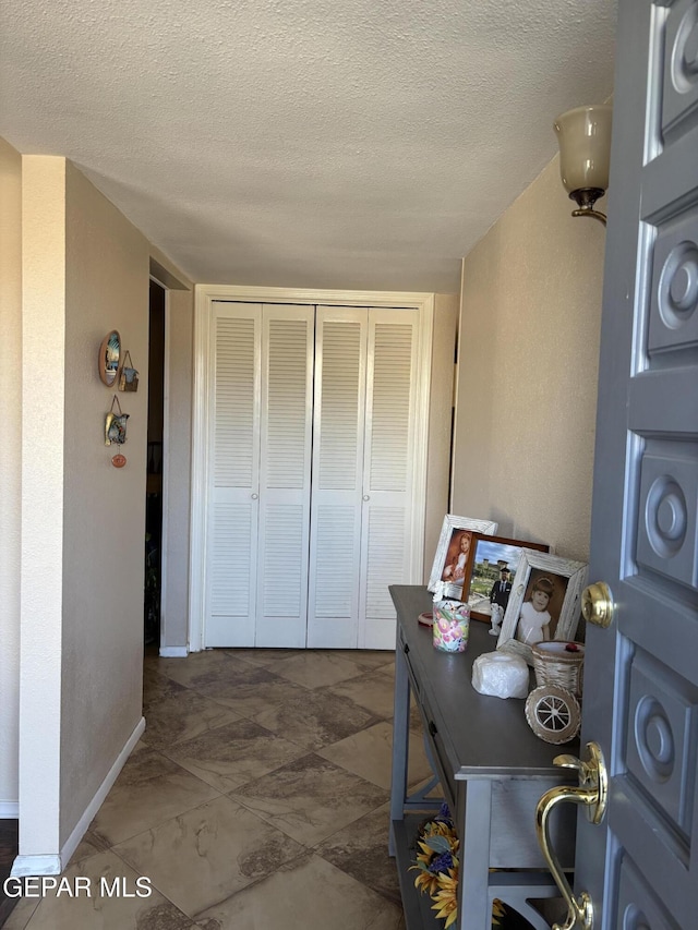 interior space featuring a textured wall, baseboards, and a textured ceiling