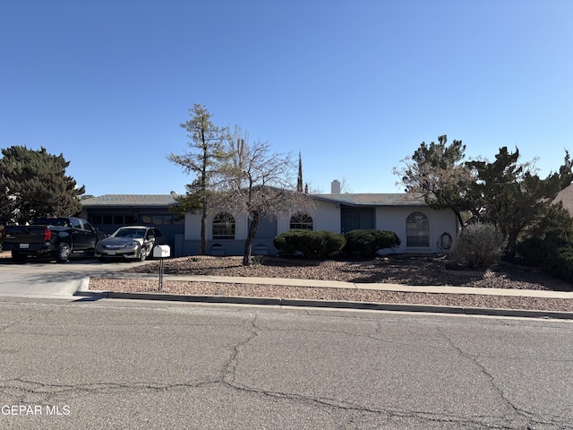 ranch-style house with concrete driveway, a garage, and stucco siding