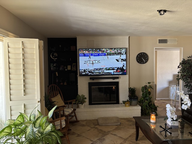 living room featuring visible vents, a fireplace, and a textured ceiling