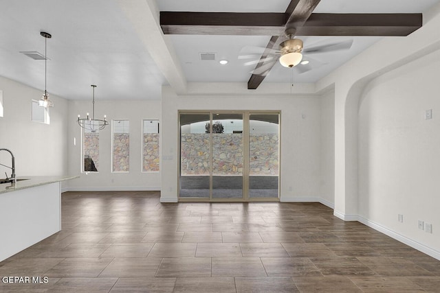 unfurnished living room with baseboards, visible vents, beam ceiling, a sink, and ceiling fan with notable chandelier