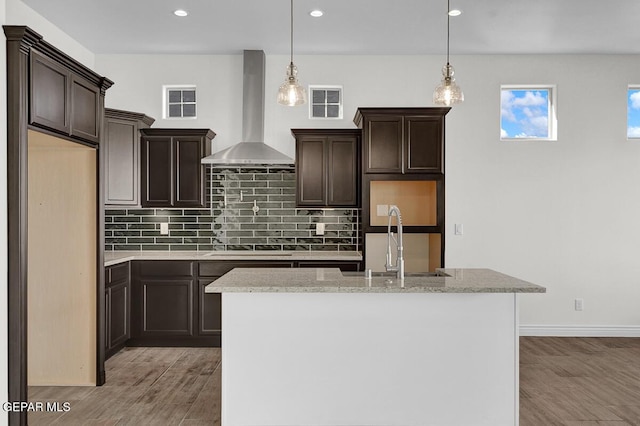 kitchen featuring visible vents, dark brown cabinets, wall chimney exhaust hood, and a sink