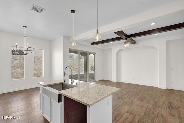 kitchen featuring visible vents, a sink, dark wood-style floors, arched walkways, and baseboards