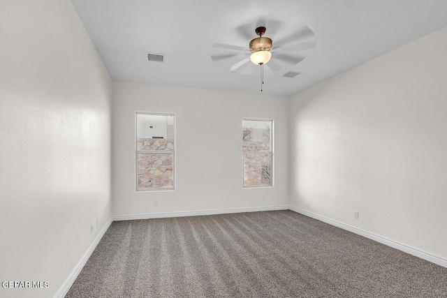 carpeted spare room with baseboards, visible vents, and ceiling fan