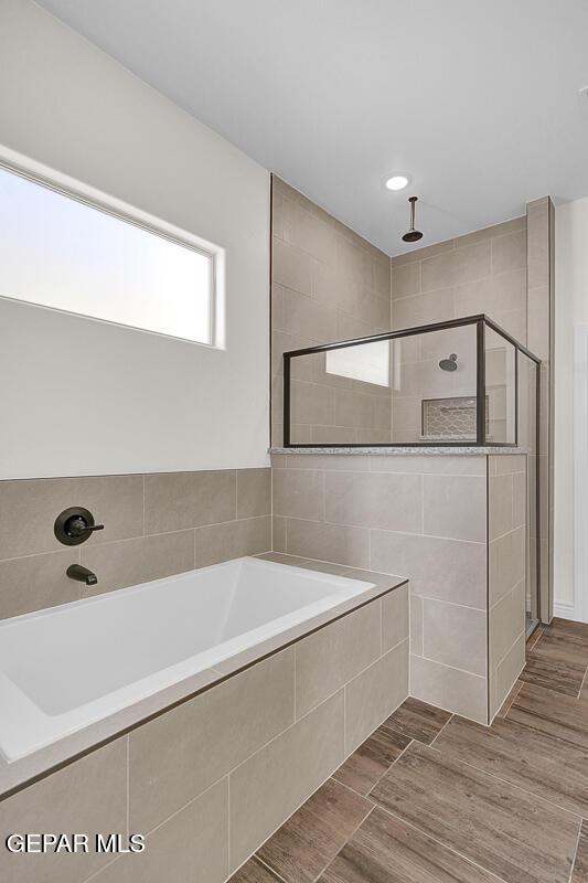 bathroom with a bath, wood tiled floor, and a tile shower