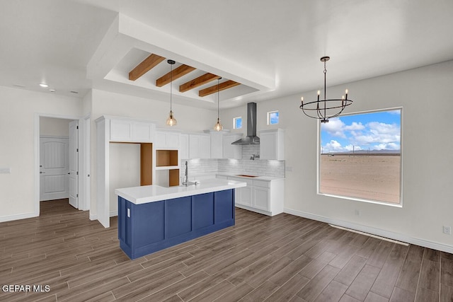 kitchen with dark wood-style floors, decorative backsplash, white cabinetry, and wall chimney range hood