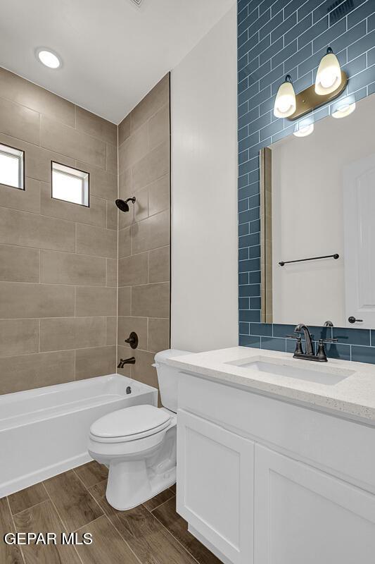 bathroom featuring vanity, toilet,  shower combination, and wood finish floors