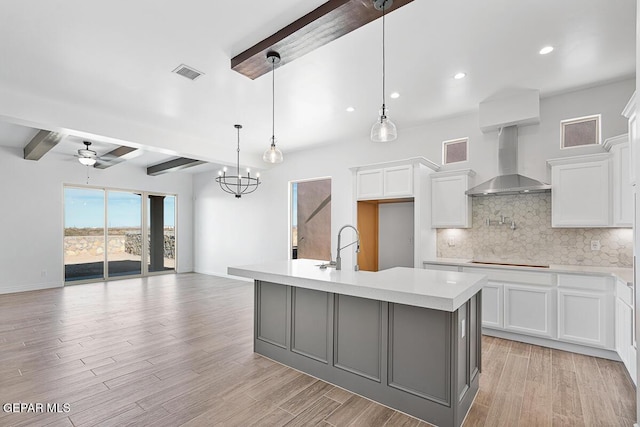 kitchen with tasteful backsplash, visible vents, wall chimney range hood, light countertops, and beam ceiling