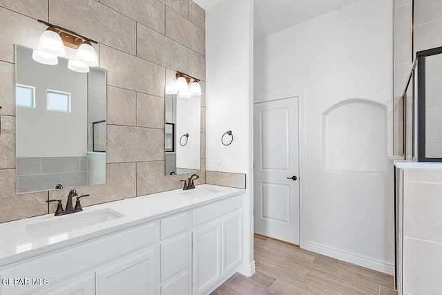 full bath featuring decorative backsplash, double vanity, wood finished floors, and a sink