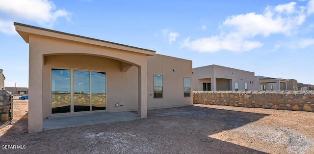 rear view of house featuring a patio, fence, and stucco siding