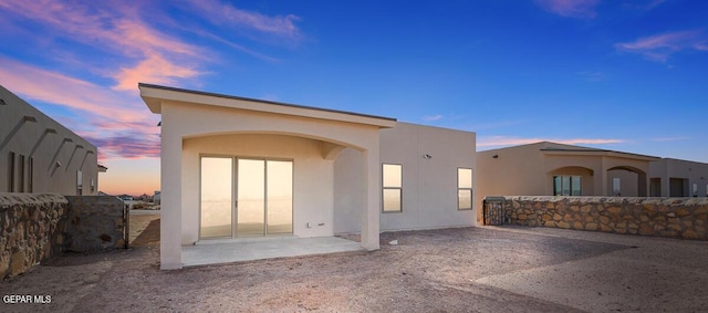 back of property at dusk with stucco siding and a patio area