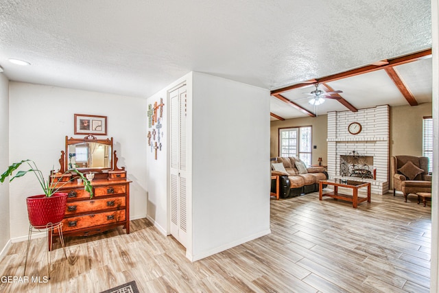 interior space featuring beam ceiling, a textured ceiling, light wood-type flooring, and baseboards