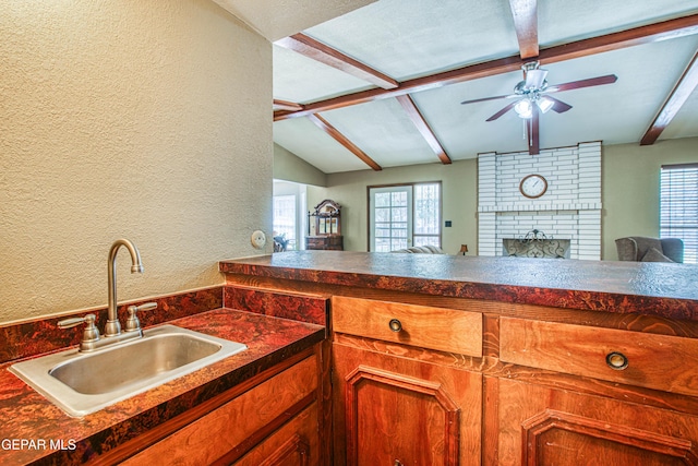 kitchen featuring a healthy amount of sunlight, a ceiling fan, lofted ceiling with beams, a sink, and dark countertops