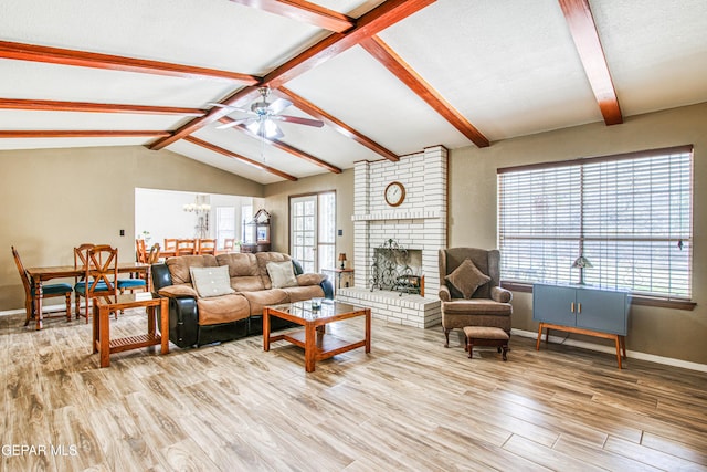 living area with vaulted ceiling with beams, baseboards, ceiling fan with notable chandelier, a fireplace, and light wood-style flooring