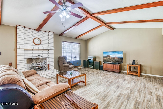 living area featuring a ceiling fan, wood finished floors, baseboards, vaulted ceiling with beams, and a brick fireplace