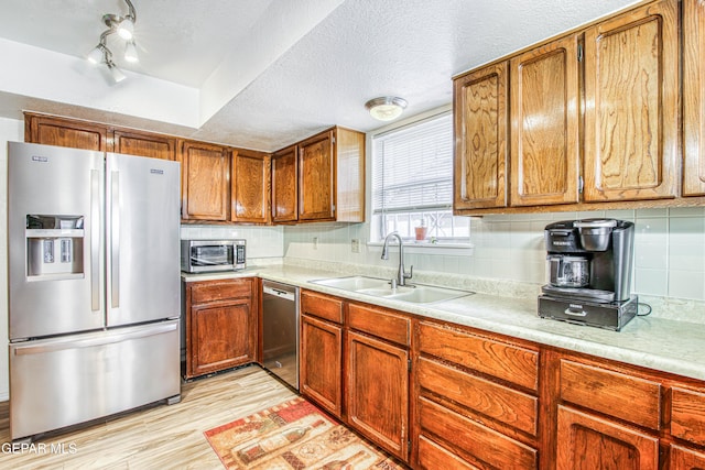 kitchen featuring a sink, stainless steel appliances, light wood-style floors, and light countertops