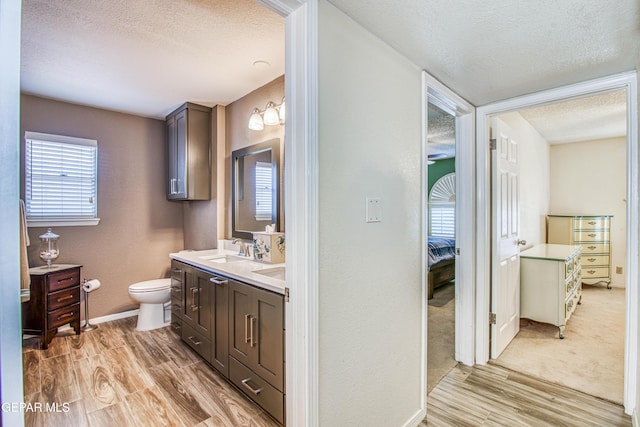 ensuite bathroom featuring toilet, wood finished floors, ensuite bathroom, and a textured ceiling