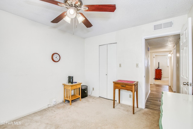 carpeted bedroom featuring visible vents, a textured ceiling, a closet, and a ceiling fan