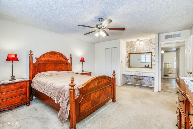 bedroom with visible vents, a ceiling fan, a textured ceiling, a closet, and light colored carpet