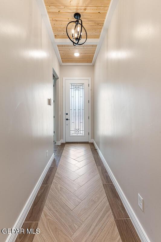 entryway featuring wooden ceiling, a notable chandelier, wood finished floors, and baseboards