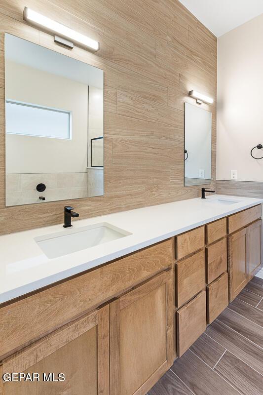 935 Bromyard Dr, Horizon City, TX 79928 - full bath with double vanity, wood finished floors, tile walls, and a sink