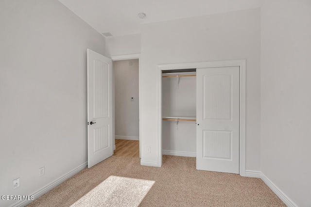 unfurnished bedroom featuring carpet, baseboards, and a closet