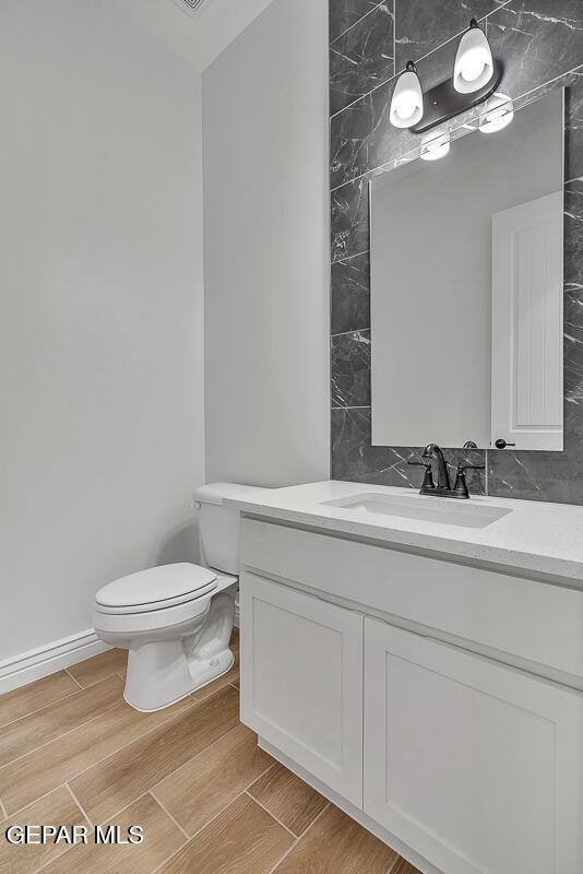 bathroom with toilet, vanity, and wood finish floors