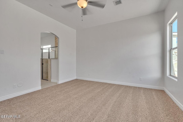 empty room with ceiling fan, light colored carpet, visible vents, and baseboards