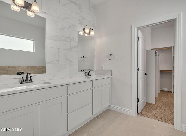 full bath featuring a sink, a walk in closet, double vanity, and tile patterned flooring