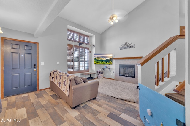 living room with stairway, wood finished floors, baseboards, high vaulted ceiling, and a fireplace