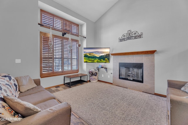 living room with baseboards, high vaulted ceiling, wood finished floors, and a tile fireplace