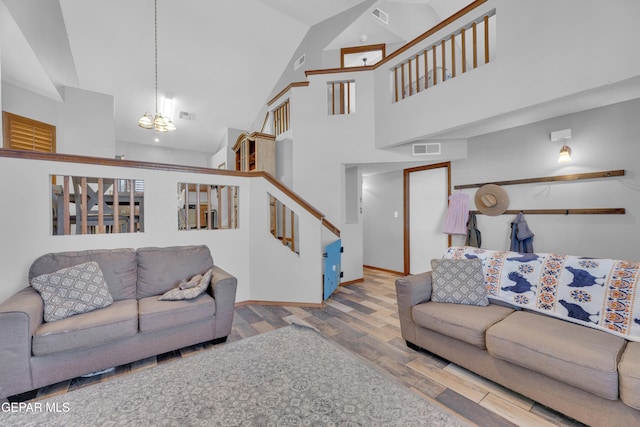 living area with visible vents, a notable chandelier, wood finished floors, and stairway