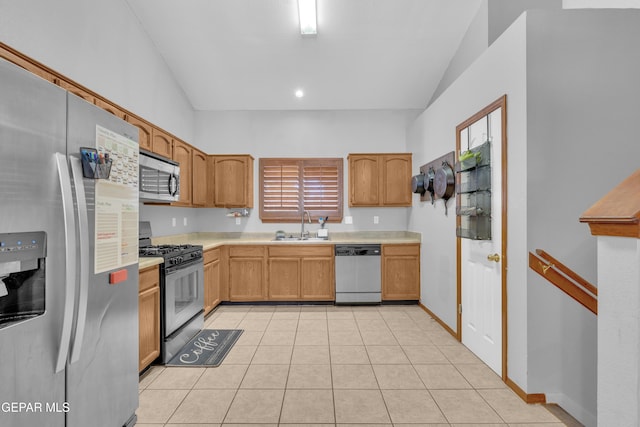 kitchen featuring light countertops, vaulted ceiling, light tile patterned flooring, stainless steel appliances, and a sink