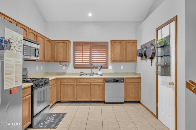 kitchen with light tile patterned flooring, a sink, light countertops, vaulted ceiling, and appliances with stainless steel finishes