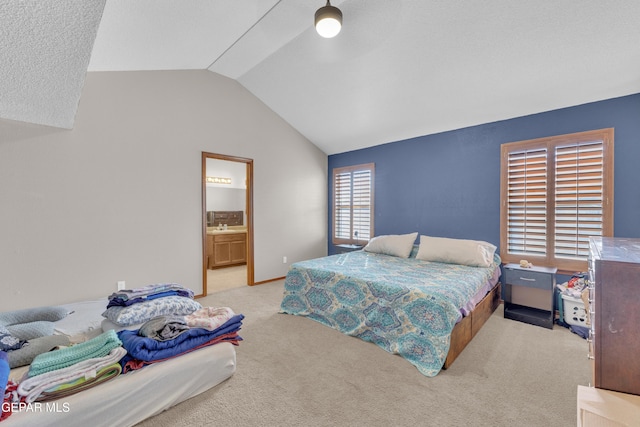 bedroom with a sink, light colored carpet, ensuite bath, and vaulted ceiling