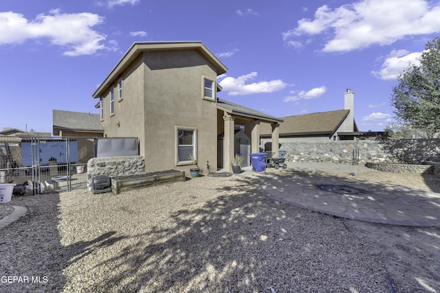 back of property with a gate, a patio area, fence, and stucco siding