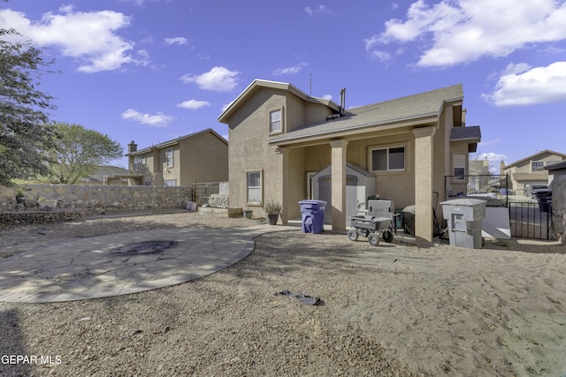 back of house with stucco siding, a storage shed, a fenced backyard, an outbuilding, and a patio