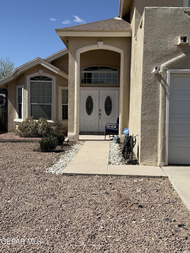 doorway to property with stucco siding and a garage