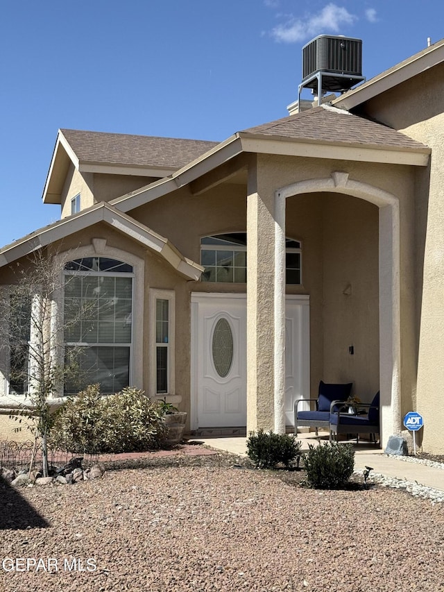 view of exterior entry featuring stucco siding and central AC