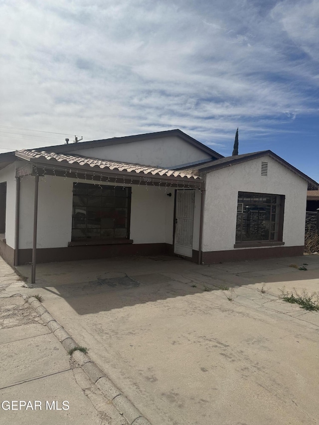 view of front of property featuring stucco siding, an attached carport, driveway, and a tiled roof