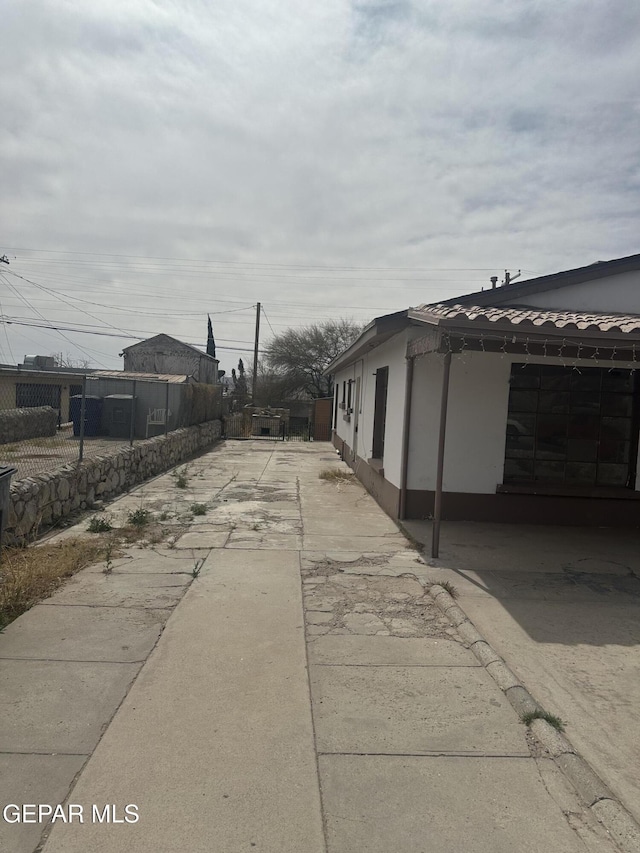 exterior space featuring stucco siding, a patio, driveway, and fence